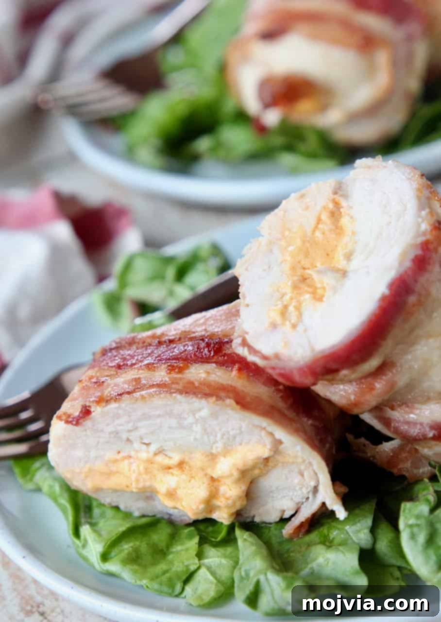 Gourmet Bacon-Wrapped Stuffed Chicken Treasure 2 Sliced stuffed chicken breast on plate with salad