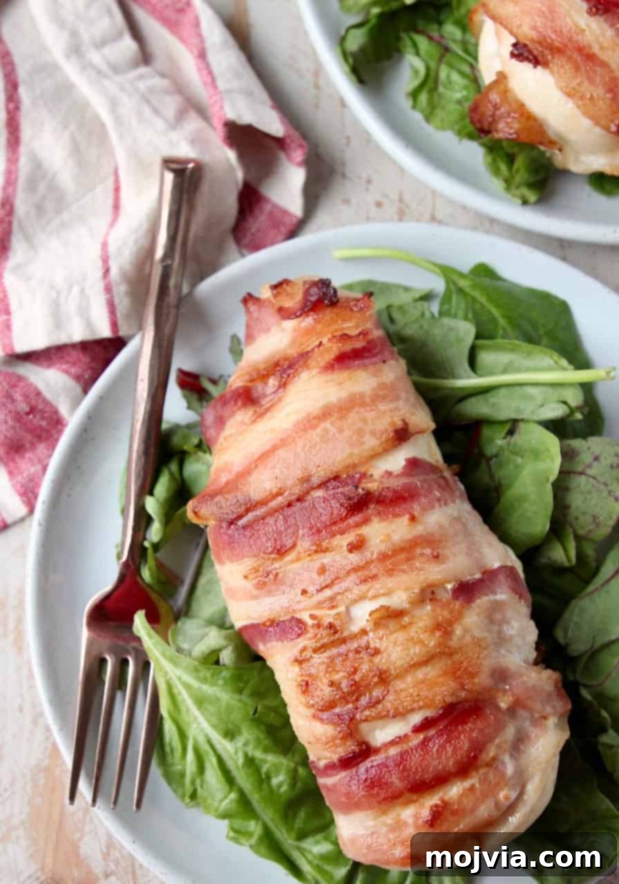 Gourmet Bacon-Wrapped Stuffed Chicken Treasure 4 Bacon wrapped chicken breast on plate with fork and salad