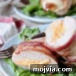Gourmet Bacon-Wrapped Stuffed Chicken Treasure 5 Bacon wrapped stuffed chicken breast cut in half on plate