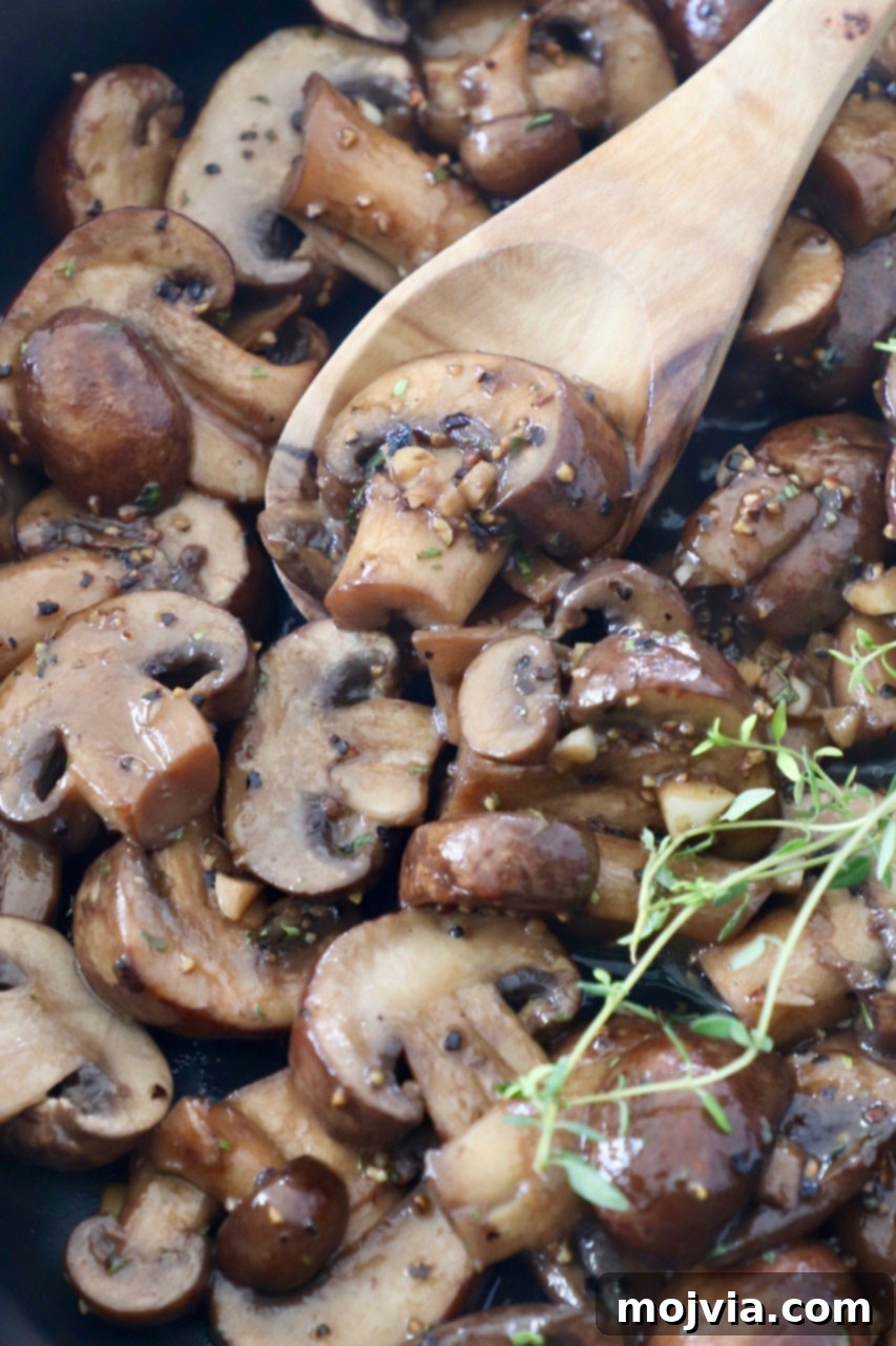 cooked sliced mushrooms in skillet with wooden spoon