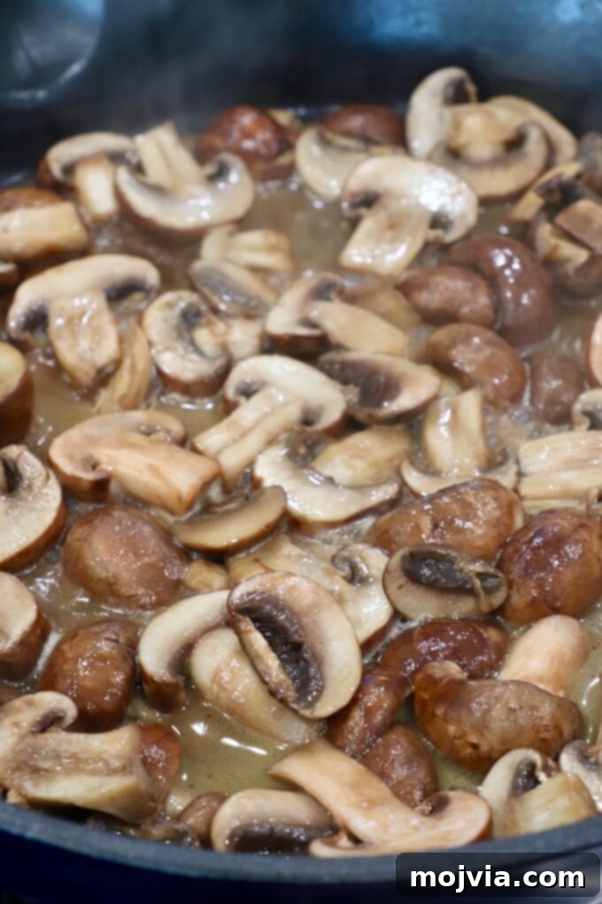 sliced mushrooms cooking in broth in skillet