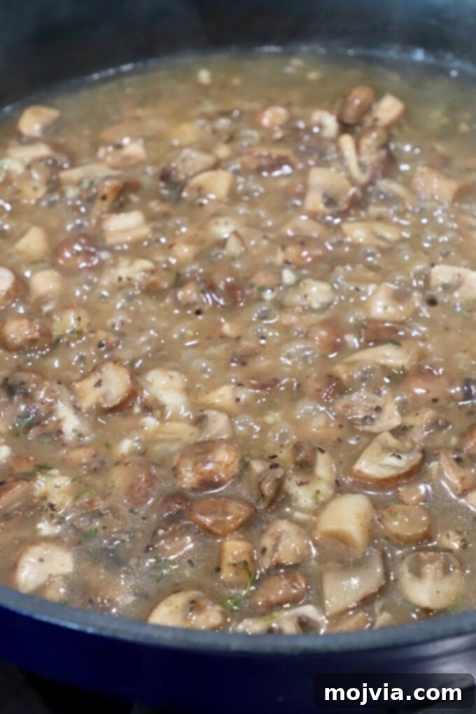 Velvety Mushroom Delight 6 Diced mushrooms simmering in vegetable broth in a skillet.