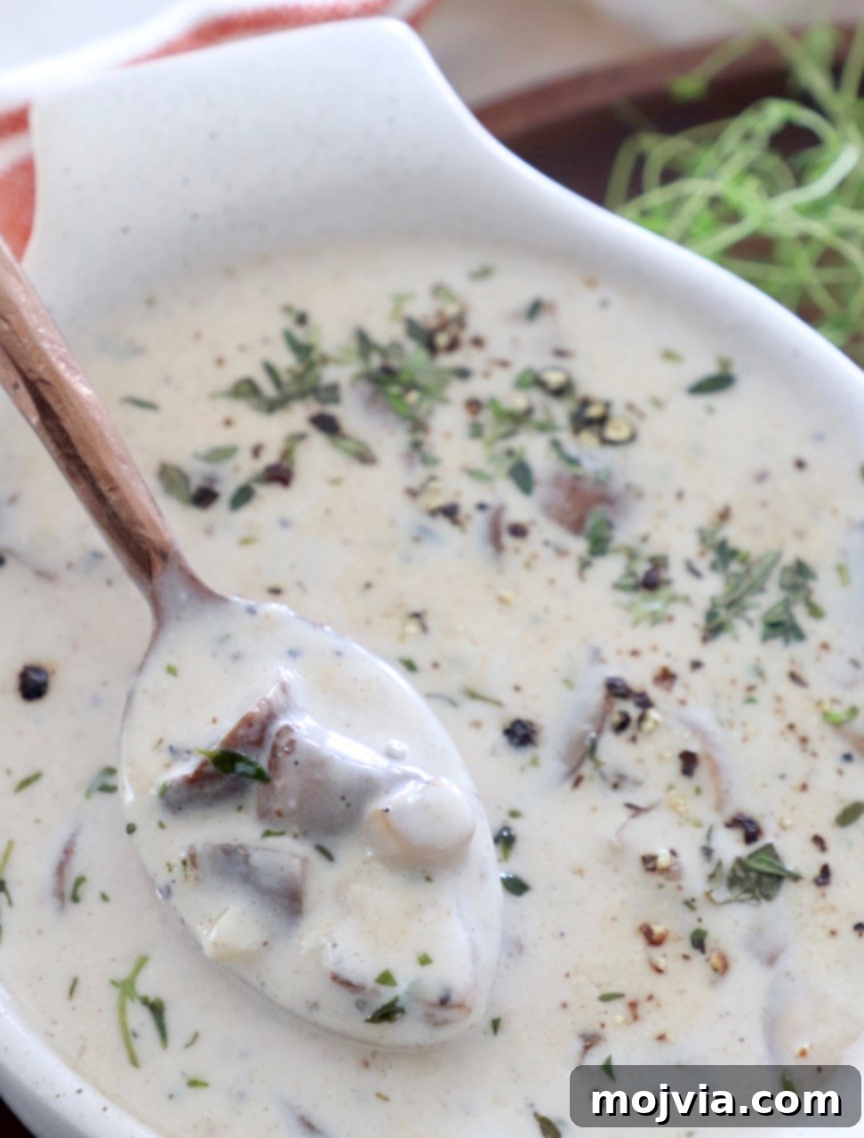 Velvety Mushroom Delight 9 Creamy mushroom soup in a bowl with a spoon, ready to be enjoyed.