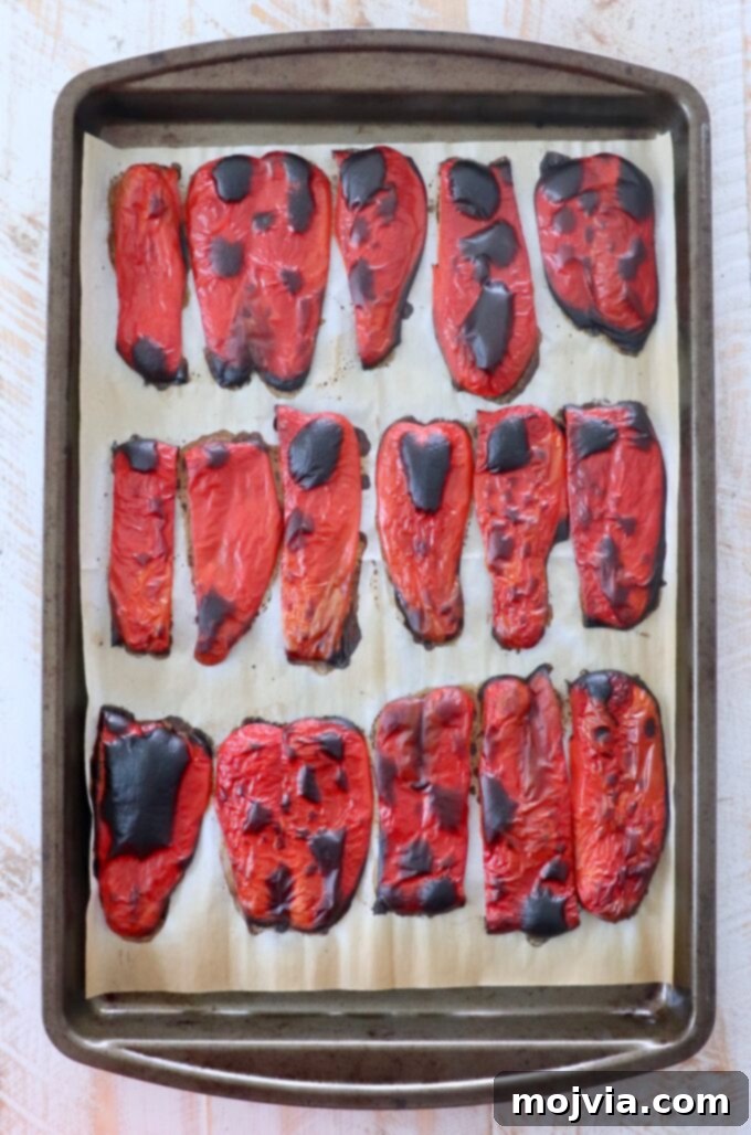 Fire Kissed Red Peppers 6 roasted red pepper slices cooling on parchment lined baking sheet with charred skins