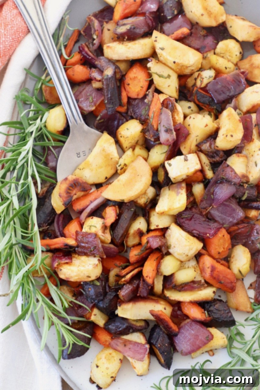 Earthy Harvest Roast 2 Roasted root vegetables on a plate with a serving fork and fresh rosemary sprigs, ready to be enjoyed.