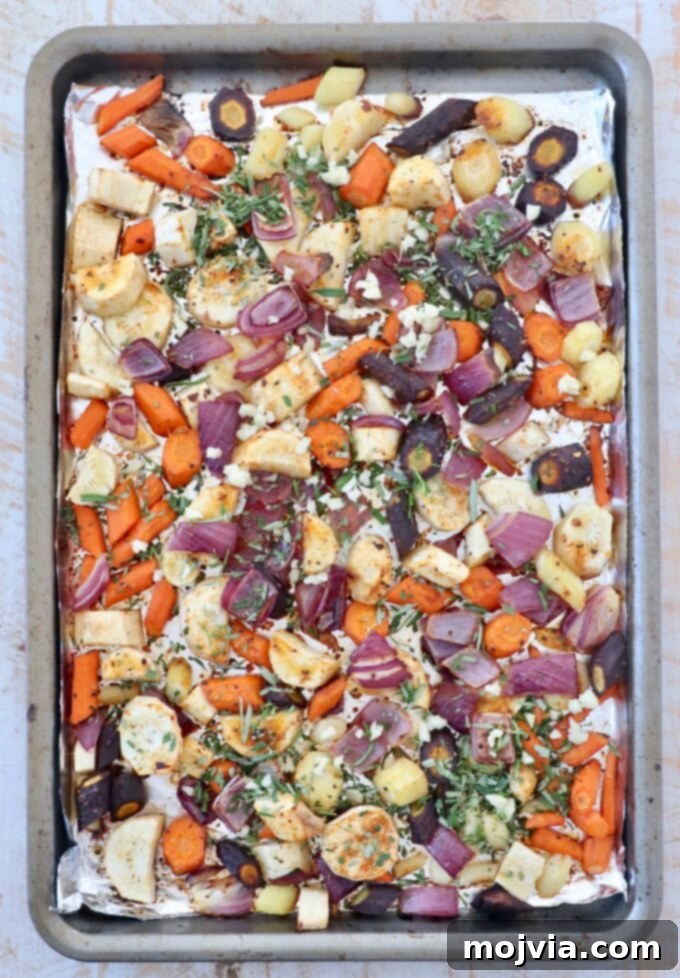 Earthy Harvest Roast 5 Diced root vegetables on a baking sheet, seasoned and mixed with fresh chopped rosemary, ready for roasting.
