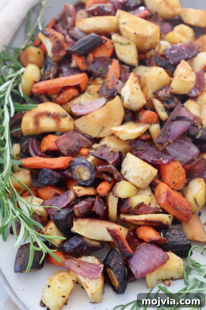 Earthy Harvest Roast 7 Roasted cubed root vegetables arranged on a plate with fresh sprigs of rosemary for garnish.