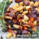 Roasted carrots, parsnips, and onions on a plate with rosemary garnish.