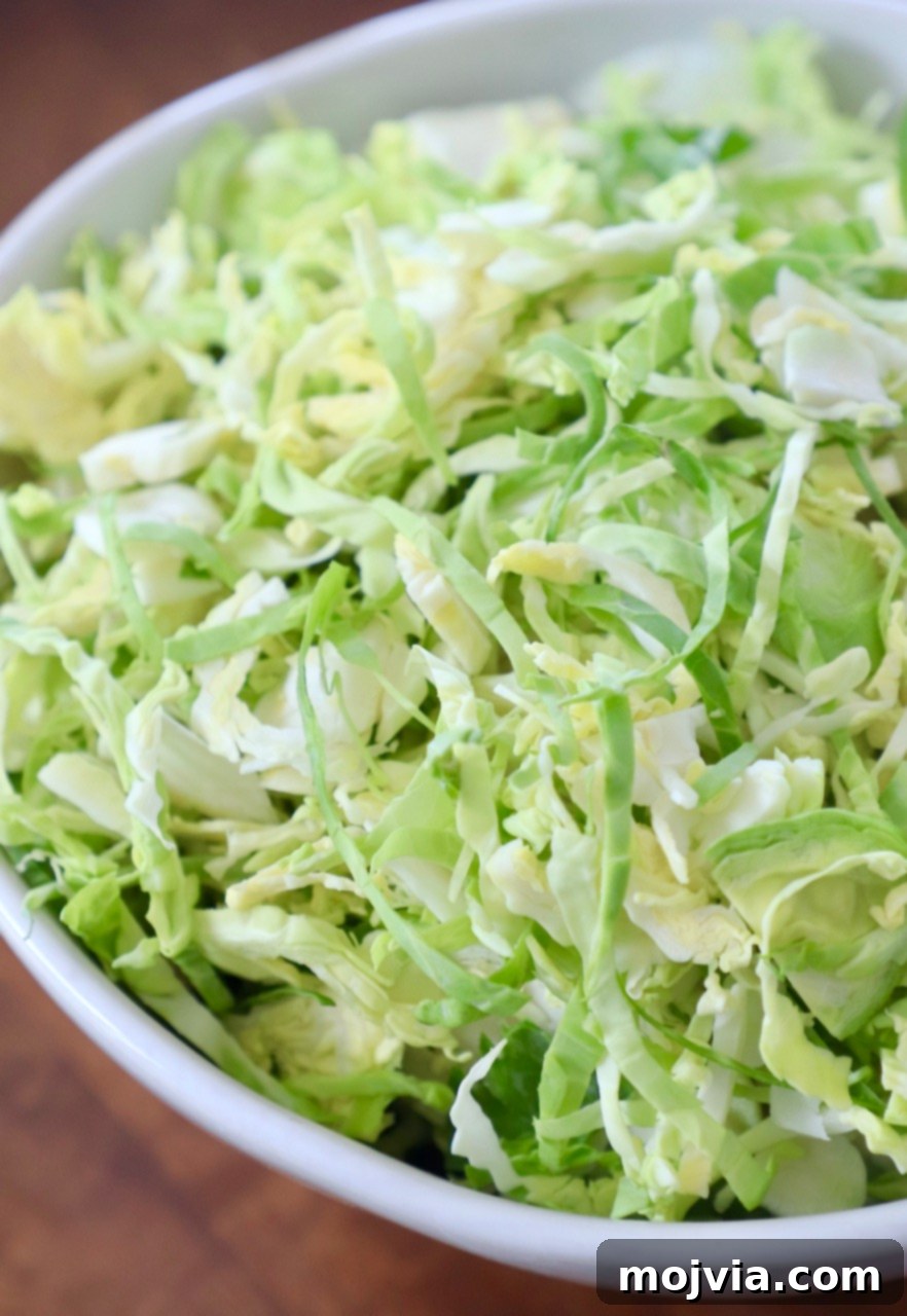 Shredding Brussels Sprouts Made Simple 2 Finely shredded brussels sprouts in a pristine white bowl, ready for cooking or salad preparation.