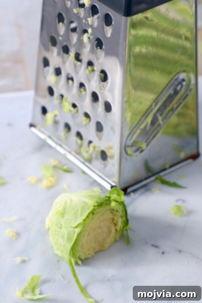 Shredding Brussels Sprouts Made Simple 8 A collection of cut Brussels sprouts next to a box grater on a cutting board, highlighting an alternative (but not recommended) method.