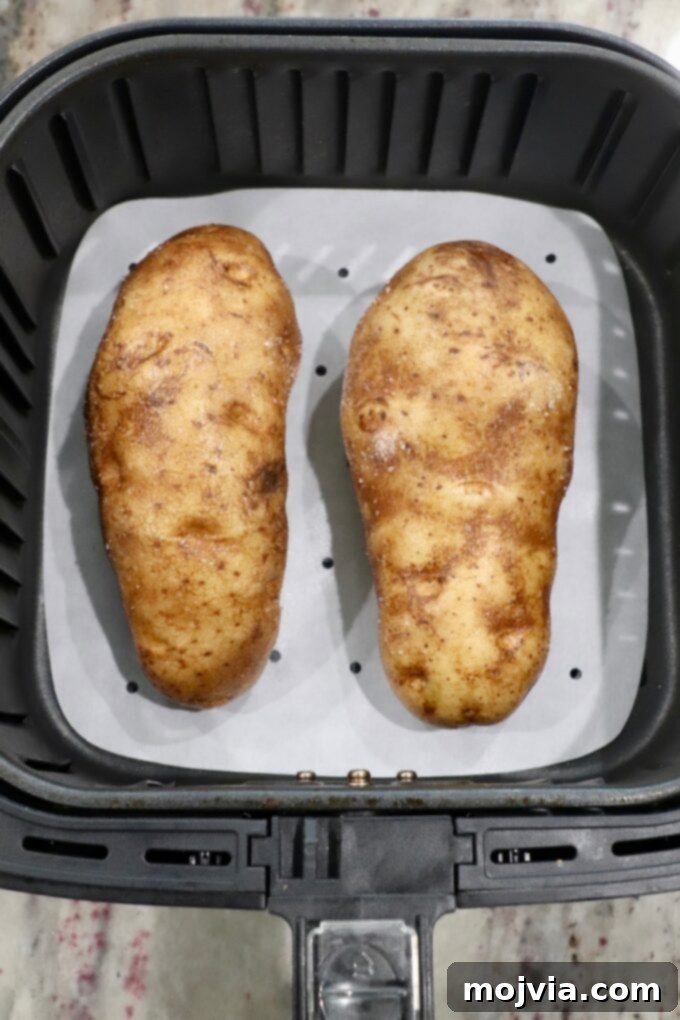 Crispy Air Fryer Baked Potatoes 3 uncooked large russet potatoes in air fryer basket