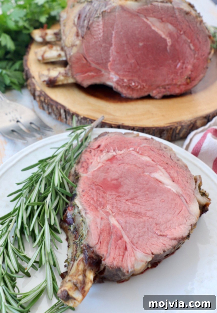 slice of prime rib with the bone on plate with fresh rosemary sprigs