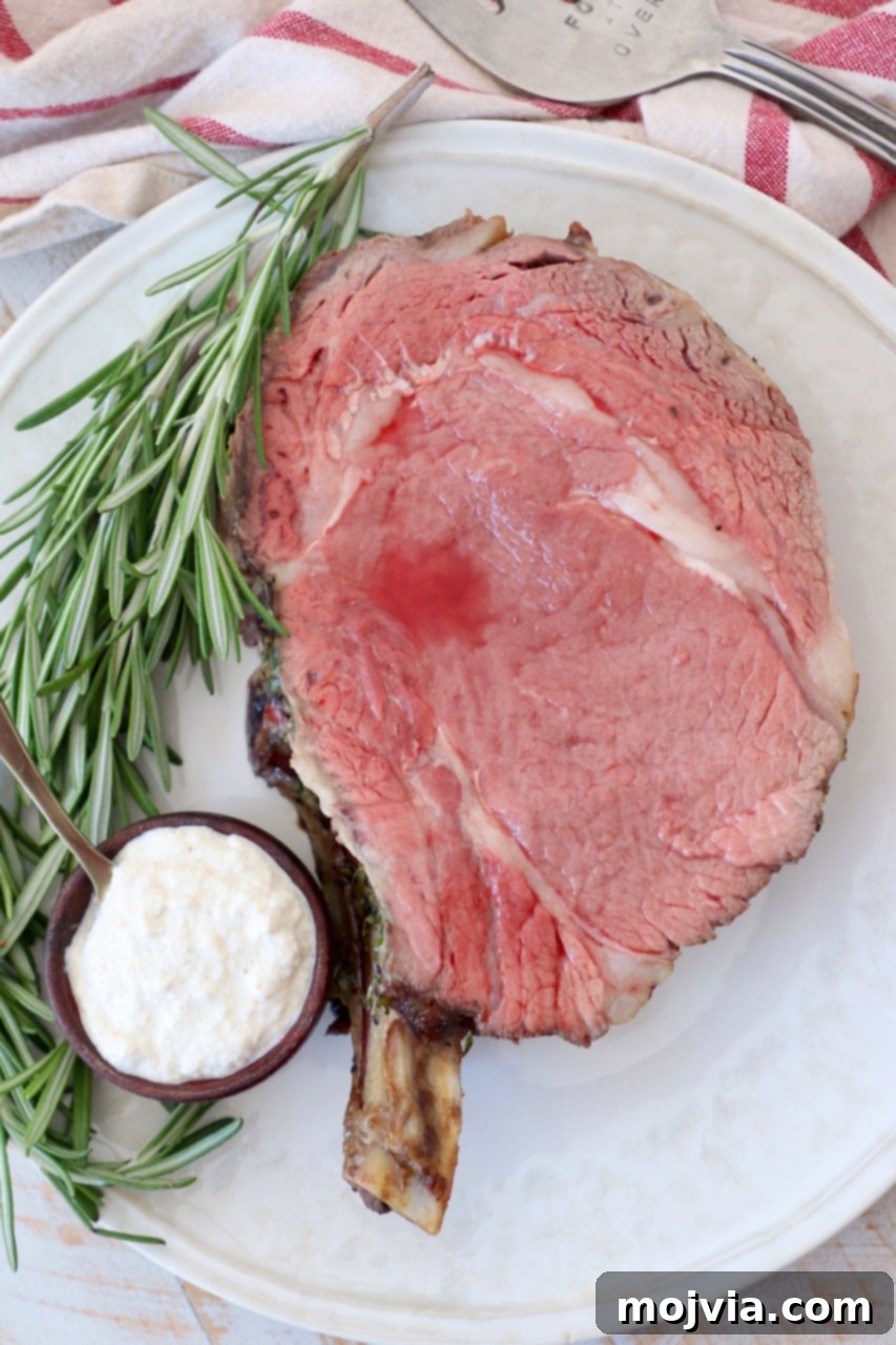 slice of cooked prime rib on plate with horseradish sauce in bowl