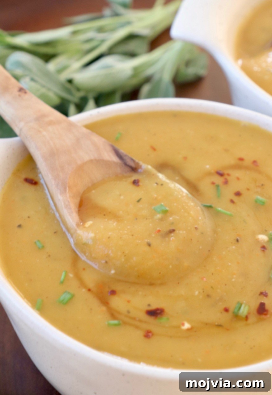 Golden Acorn Squash Comfort 2 A comforting bowl of roasted acorn squash soup, garnished and ready to be enjoyed with a wooden spoon.