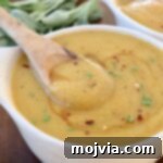 Acorn squash soup in bowl with wooden spoon