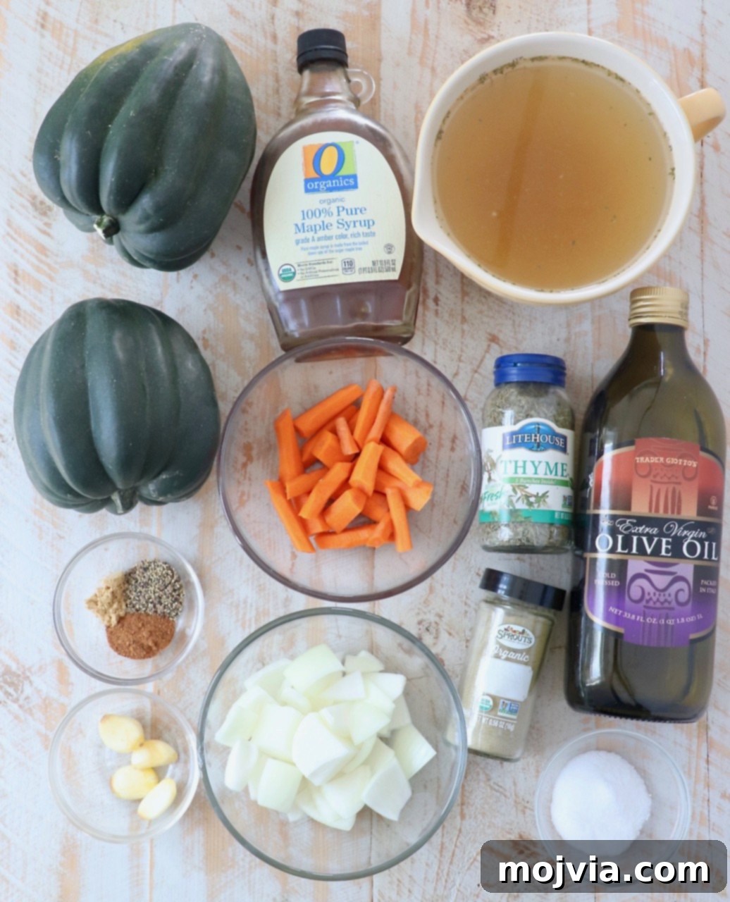 Golden Acorn Squash Comfort 3 Fresh ingredients for acorn squash soup, including squash, carrots, onions, and spices, arranged on a wooden board.