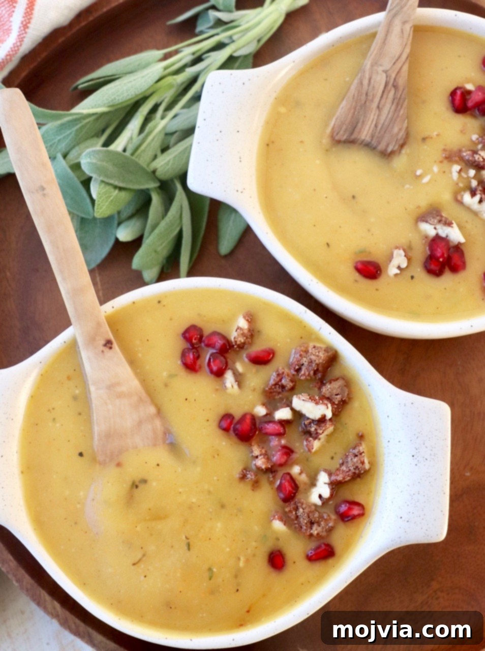 Golden Acorn Squash Comfort 8 Two bowls of acorn squash soup, beautifully garnished with walnuts and pomegranate seeds, with spoons ready.