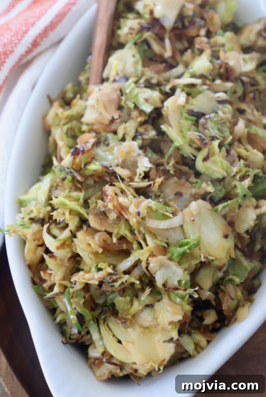 Sauteed shredded brussels sprouts in a elegant white serving dish with a fork, ready to be enjoyed.