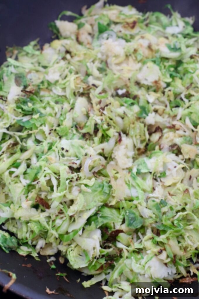 Perfectly cooked and caramelized shredded brussels sprouts in a cast iron skillet, showing the golden-brown crispy edges.
