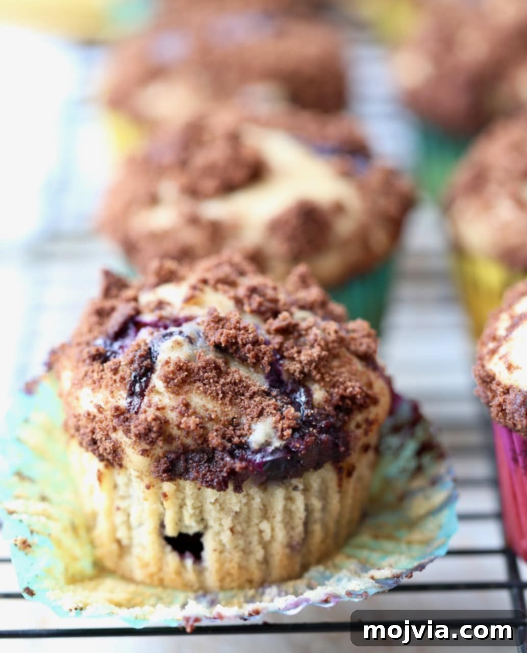 Close-up of a Blueberry Cream Cheese Muffin with Chocolate Crumble, wrapper peeled back to reveal the fluffy texture