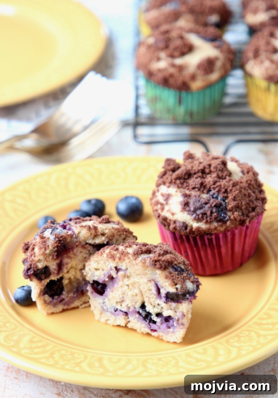 Freshly baked Blueberry Cream Cheese Muffins with Chocolate Crumble, garnished with fresh blueberries on a yellow plate