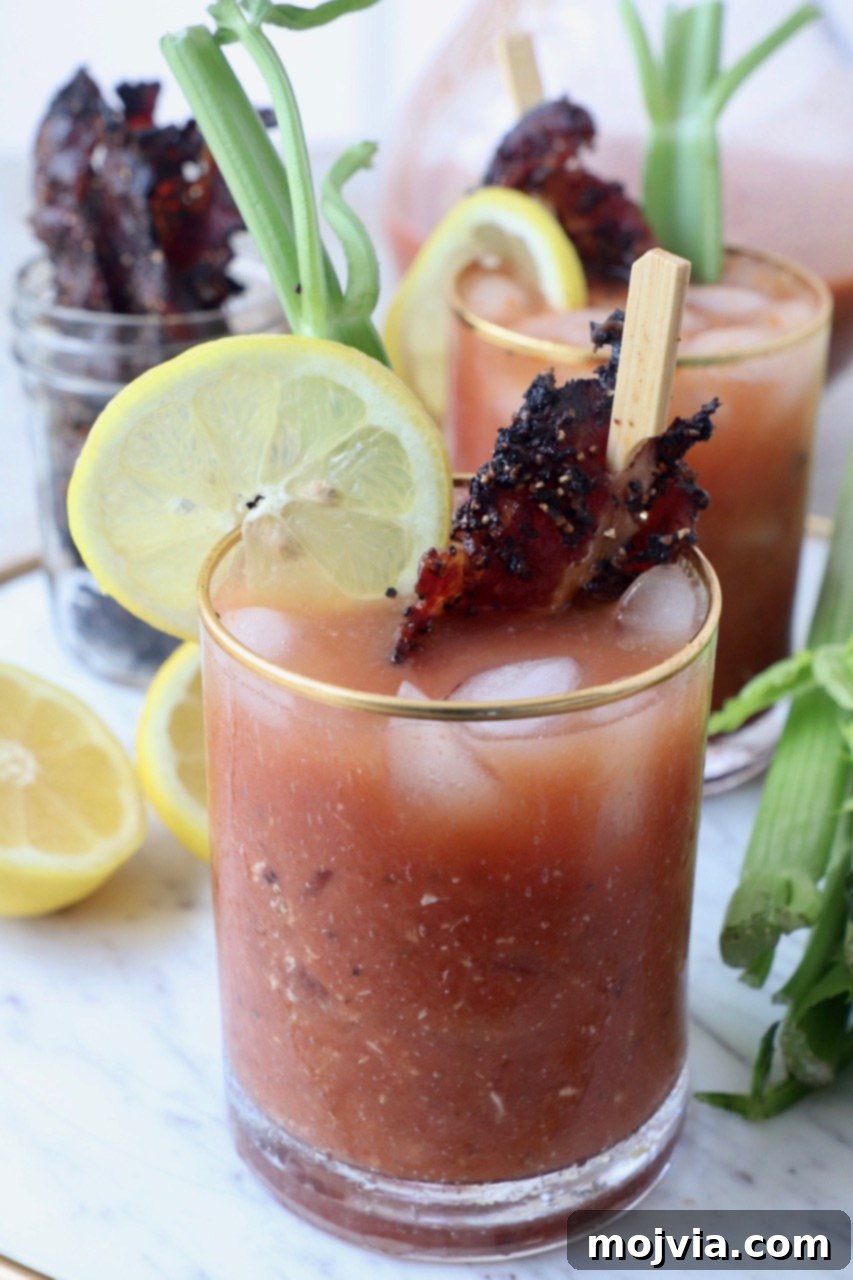 A perfectly garnished Bloody Mary cocktail in a glass with candied bacon and a lime wedge