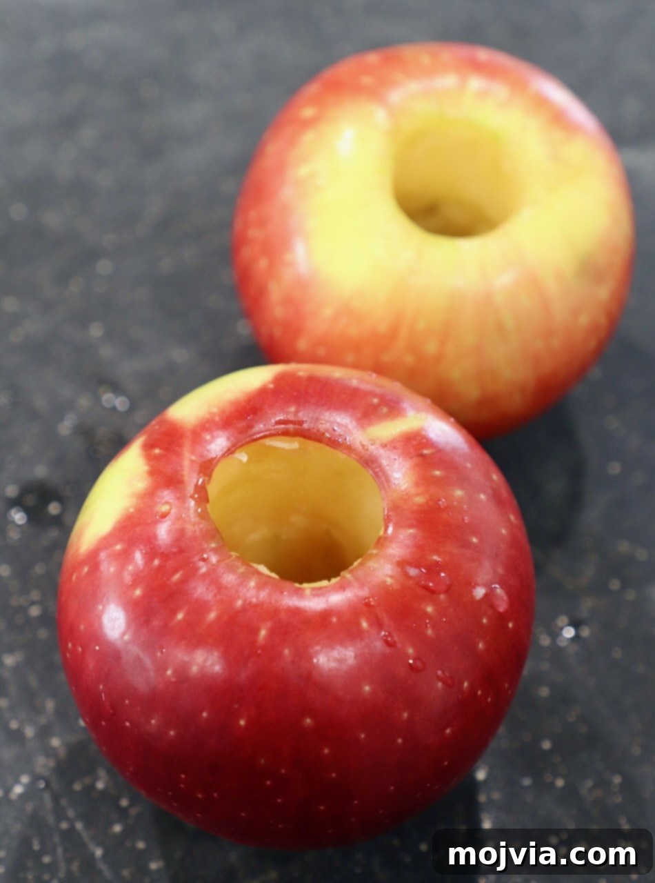 Two cored apples ready for slicing on a wooden cutting board.
