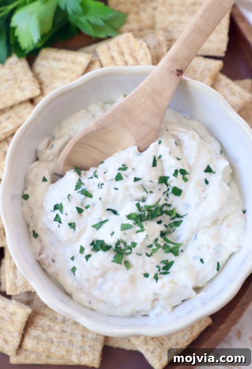 Sweet Roasted Garlic Spread 9 Close-up of creamy roasted garlic dip in a white bowl with a wooden spoon.