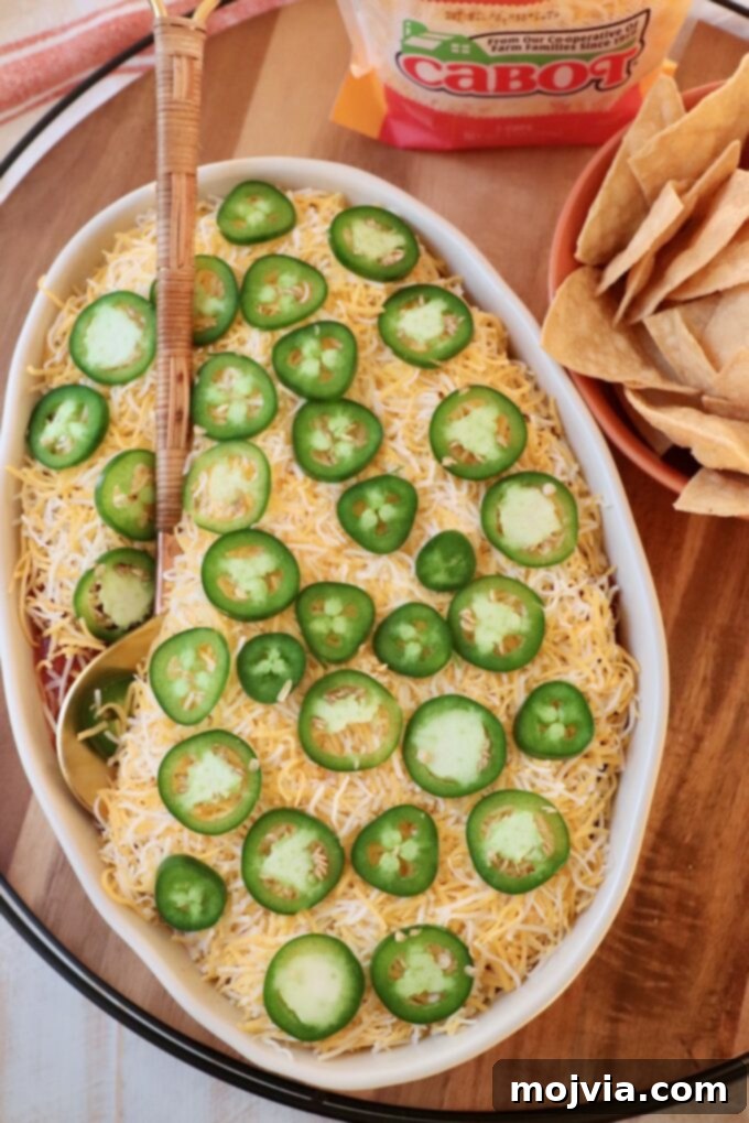 Sizzling Fajita Seven-Layer Dip 12 The fully assembled seven layer dip in a casserole dish with a serving spoon