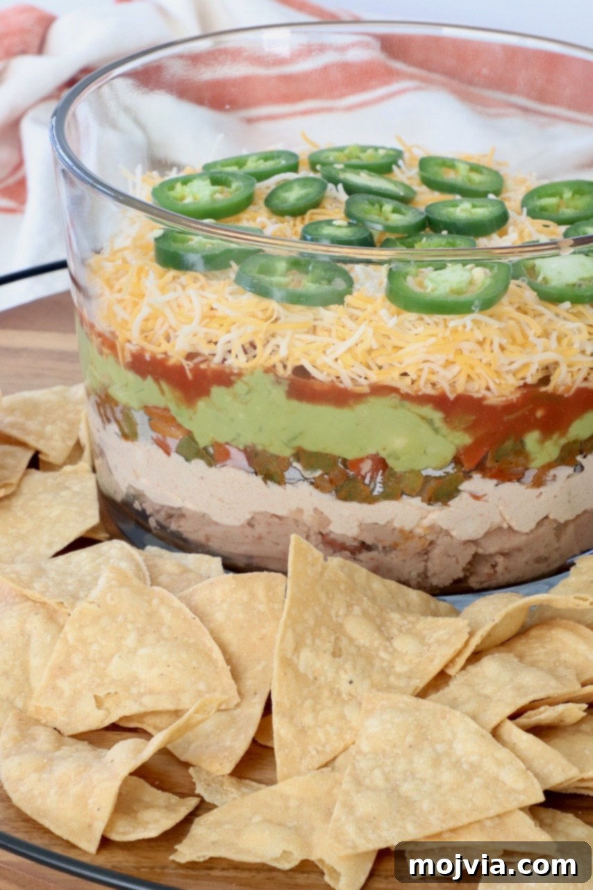 Sizzling Fajita Seven-Layer Dip 14 Serving tray featuring Fajita-Style 7 Layer Dip in a glass trifle bowl, surrounded by a generous amount of tortilla chips
