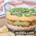 Sizzling Fajita Seven-Layer Dip 15 A vibrant seven-layer dip in a clear glass trifle bowl