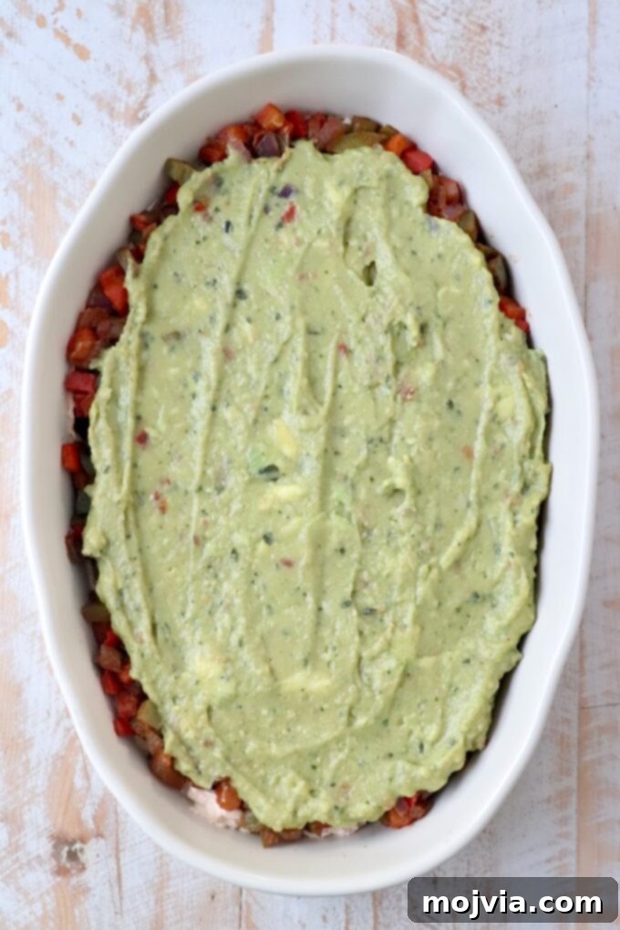 Sizzling Fajita Seven-Layer Dip 9 Smooth guacamole spread over the fajita vegetables layer