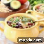 Crockpot Taco Soup in yellow crock with gold spoon, topped with cheddar cheese and fresh cilantro