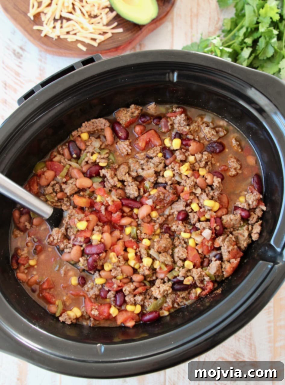 Crockpot taco soup, showing a close-up of the rich texture with corn, beans, tomatoes, and ground beef visible, indicating a hearty and flavorful meal.