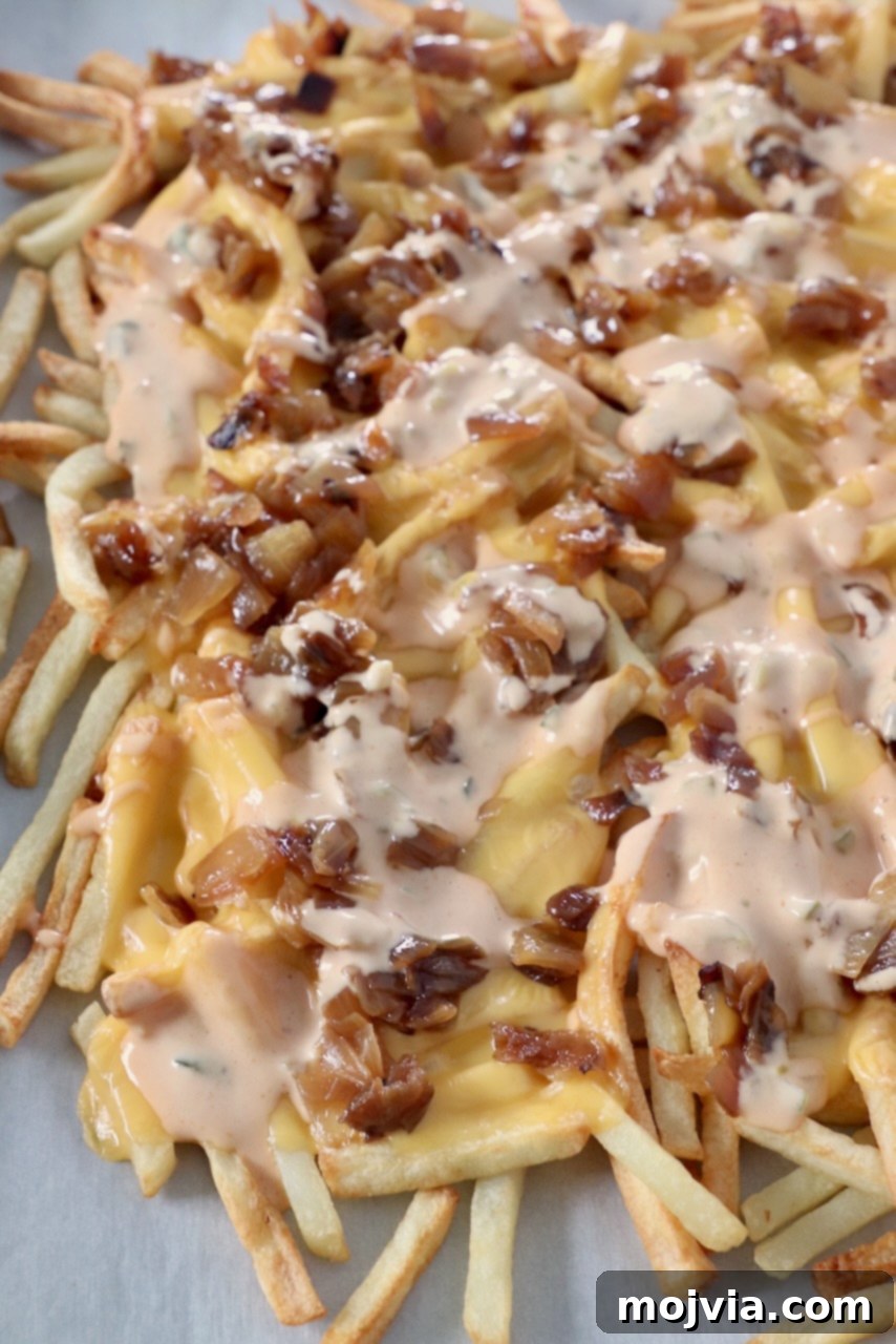 Secret Sauce Loaded Fries 2 cooked french fries on baking sheet covered with cheese, caramelized onions and burger sauce