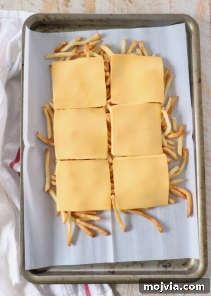 Secret Sauce Loaded Fries 4 cooked fresh fries on baking sheet topped with slices of cheese