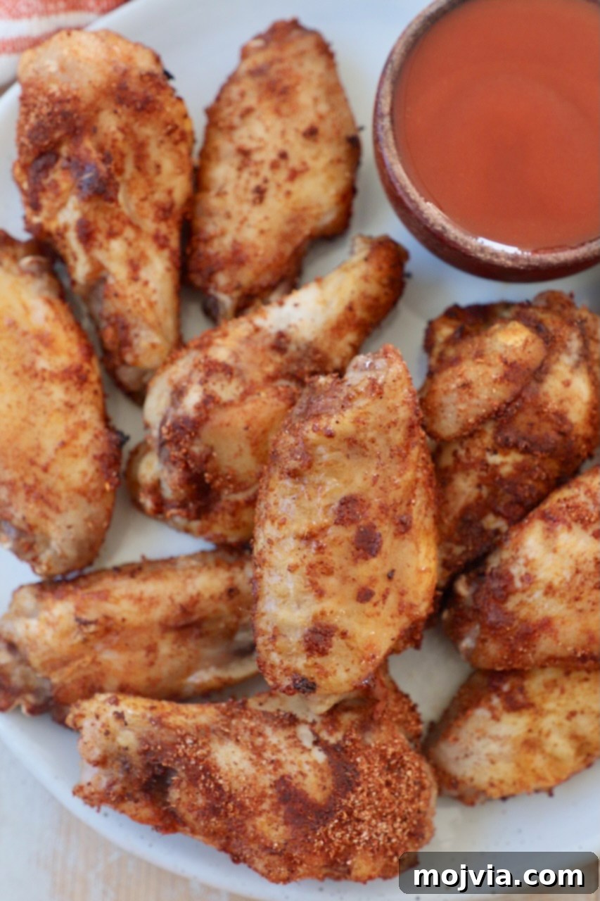 Sous Vide Wings: Crispy, Juicy Perfection 10 cooked chicken wings on plate with side of buffalo sauce in small bowl