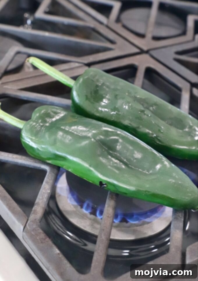 Smoky Roasted Poblanos 7 Raw poblano peppers placed directly over an open gas flame on a stovetop, ready for charring.