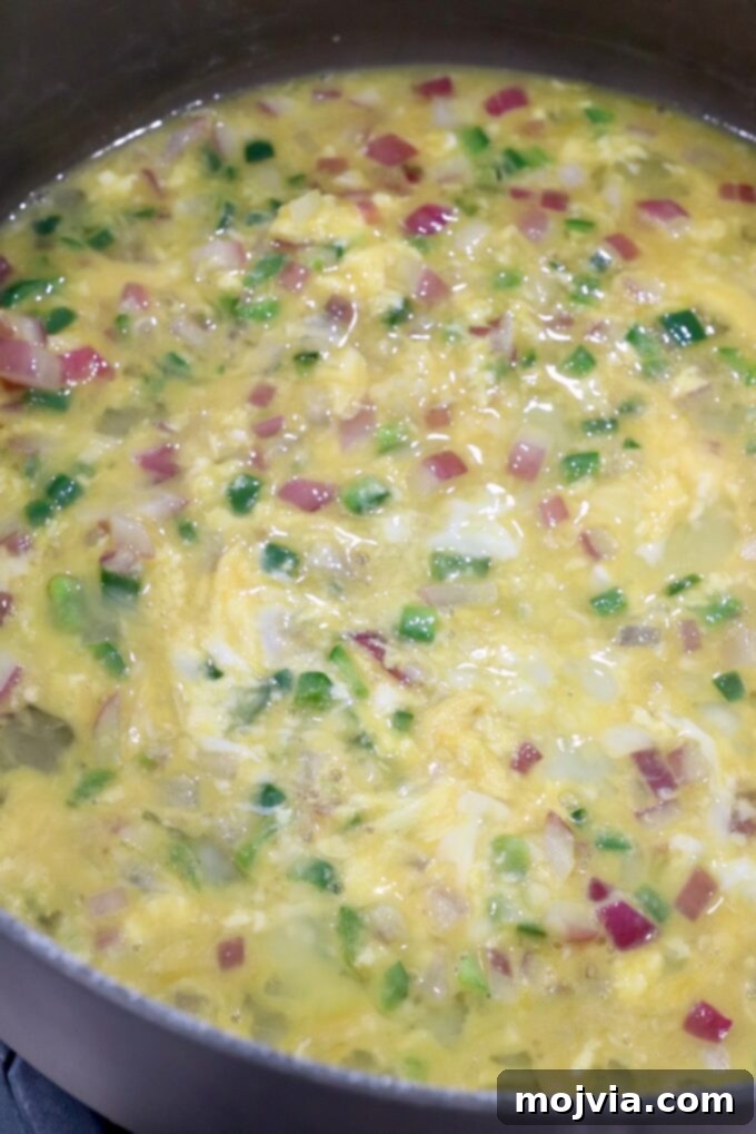 Classic Migas 6 Whisked eggs poured into a skillet with sautéed jalapeños and onions, beginning the scrambling process for Migas.
