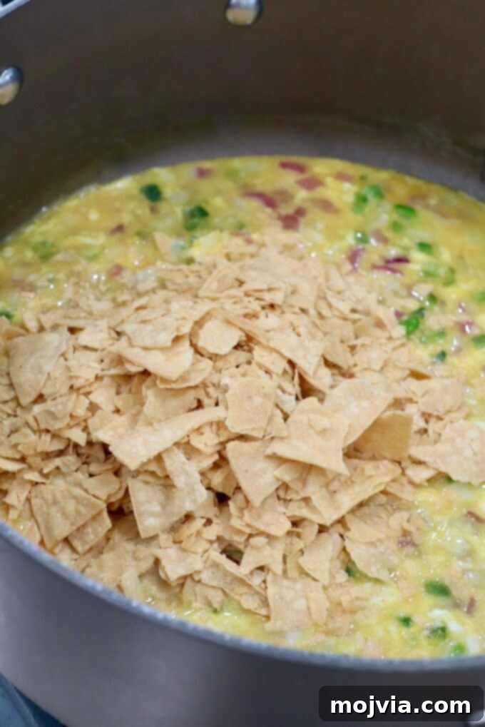 Classic Migas 7 Crumbled tortilla chips added to the skillet with scrambled eggs, jalapeños, and onions, completing the Migas mixture.