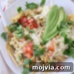 Migas on a plate with fork, topped with sliced avocado