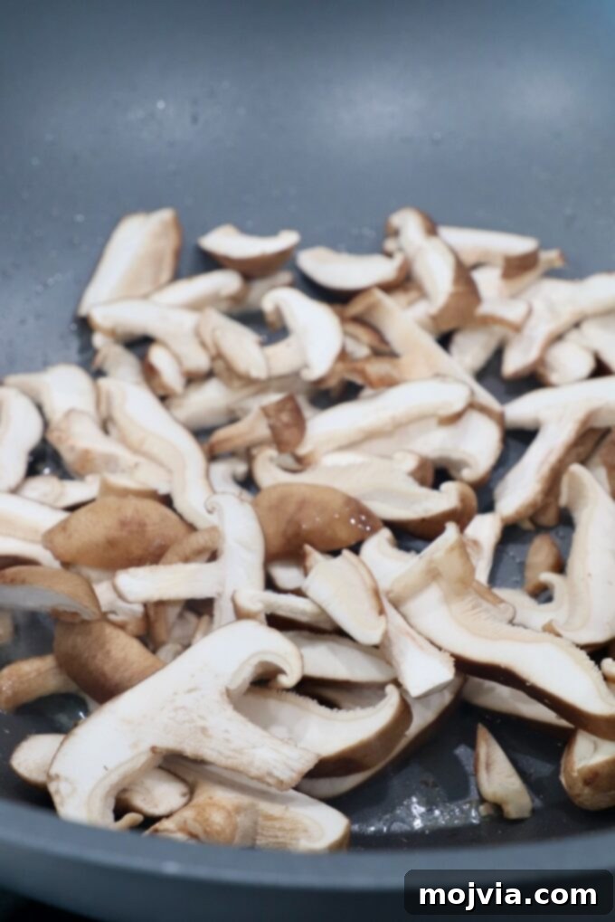 Golden Miso Noodle Perfection 5 Thinly sliced shiitake mushrooms added to the wok, soaking up the savory flavors of the pork drippings.