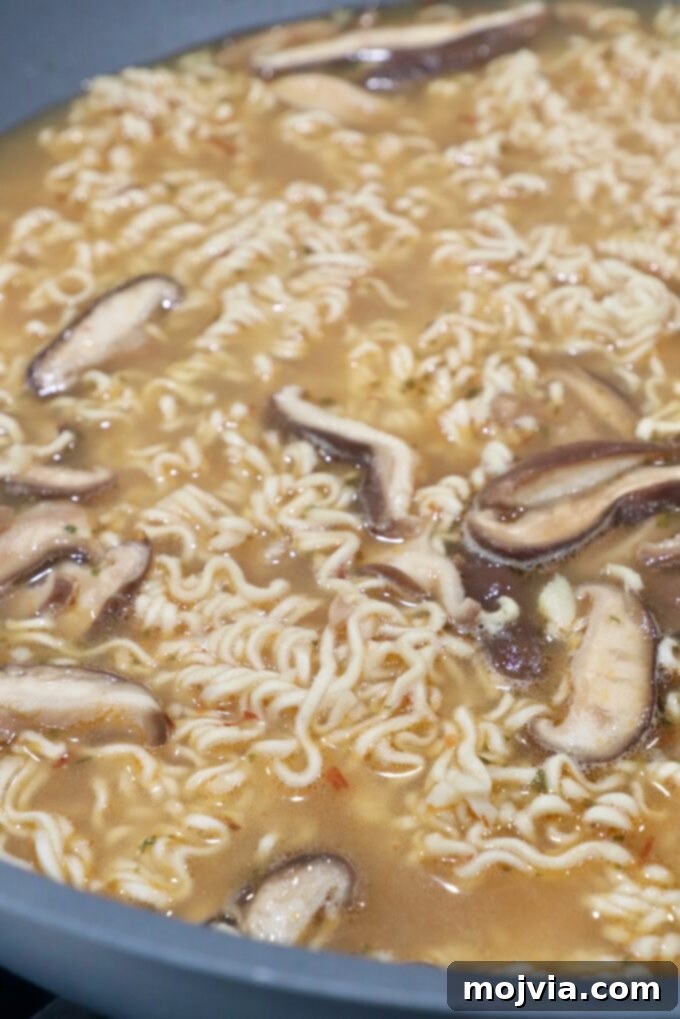 Golden Miso Noodle Perfection 8 Ramen noodles submerged in the rich, simmering broth with mushrooms in a large wok, cooking to tender perfection.