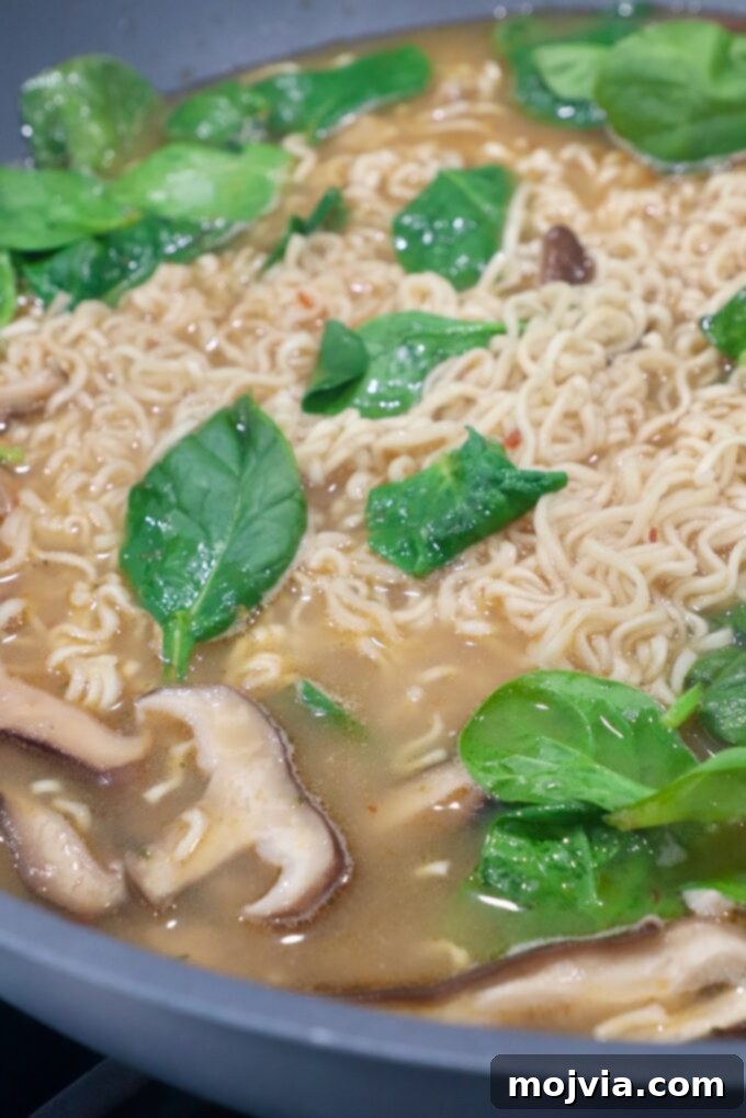 Golden Miso Noodle Perfection 9 Fresh spinach and cooked pork added to the wok with ramen noodles and mushrooms, integrating into the hot, flavorful Miso Ramen soup.