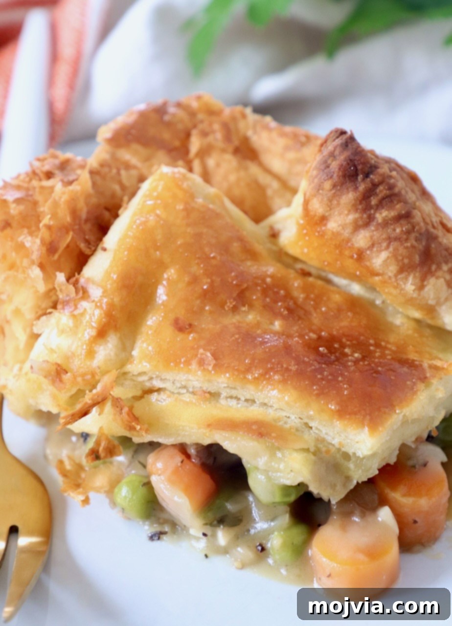 Rustic Vegetable Pot Pie 14 piece of vegetable pot pie on white plate with fork, showing steam and golden crust