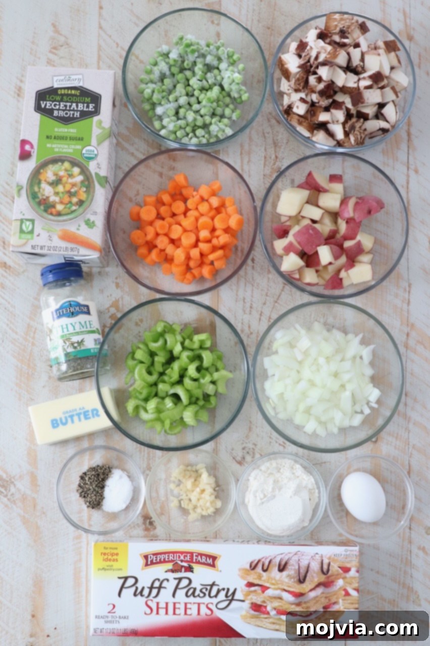 Puff-Pastry Garden Feast 3 A vibrant display of fresh ingredients for vegetarian pot pie including thawed puff pastry, red potatoes, carrots, yellow onions, celery, portobello mushrooms, garlic cloves, all-purpose flour, vegetable broth, dried thyme, and frozen peas.
