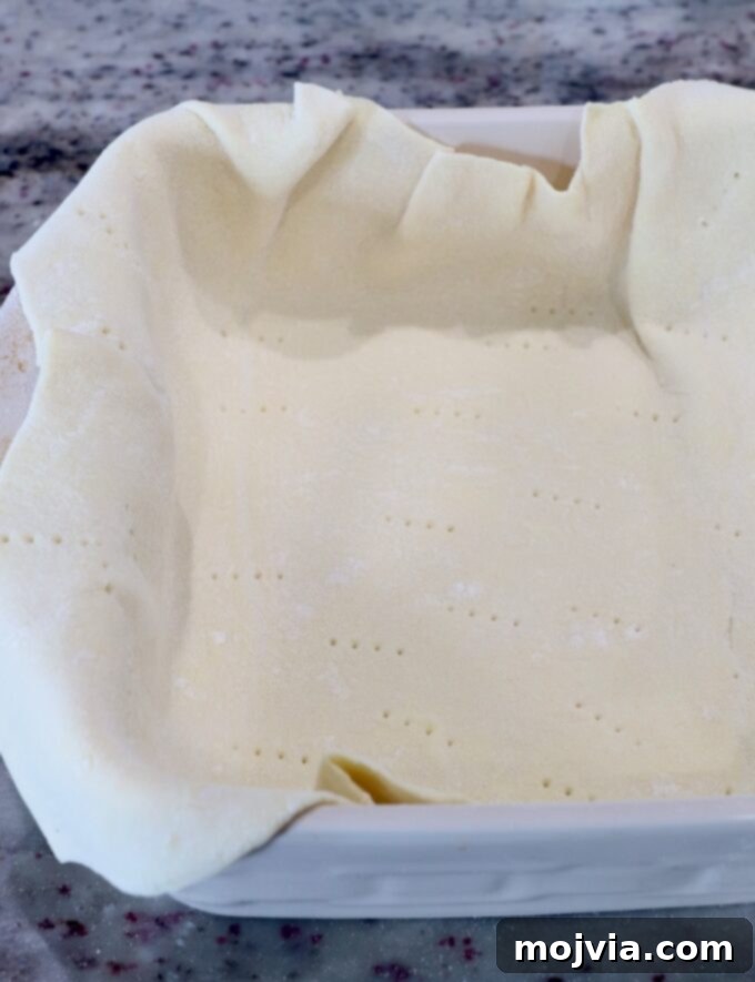 Puff-Pastry Garden Feast 4 Puff pastry dough neatly placed and pressed into a square baking dish, ready for its initial blind bake to create a crisp bottom crust.