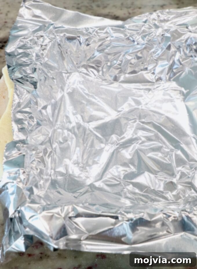 Puff-Pastry Garden Feast 5 A piece of aluminum foil securely covering the puff pastry in the baking dish, ensuring the crust bakes without over-browning during the blind baking process.