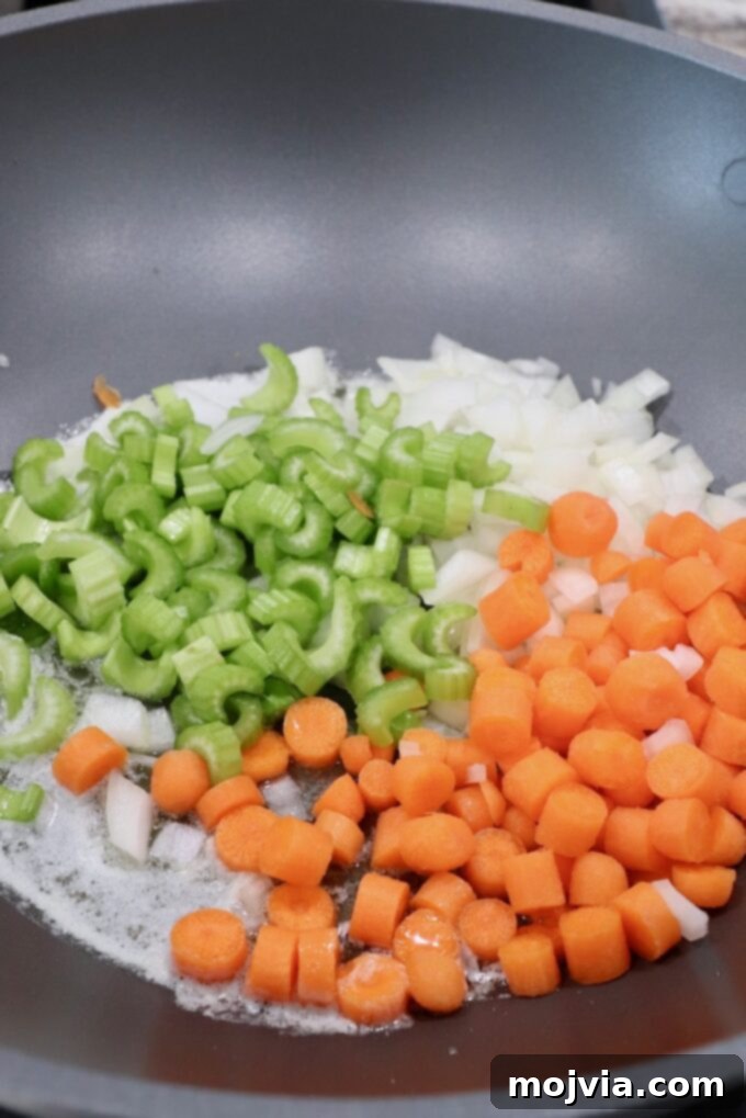 Puff-Pastry Garden Feast 6 Diced carrots, celery, and onions glistening in a large skillet, actively sautéing to form the aromatic flavor base for the pot pie filling.