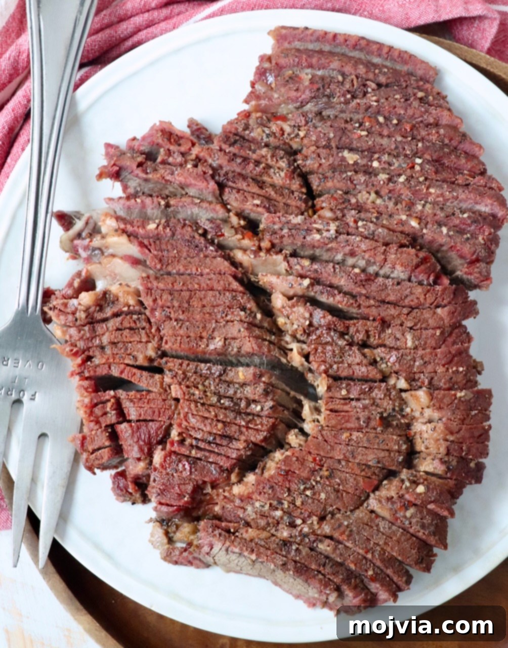 Perfectly sliced smoked chuck roast resting on a plate with a serving fork, highlighting its tender texture and juicy interior.